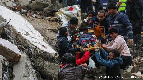 Personas ayudando a rescatar a una persona en un terremoto en Turquía.