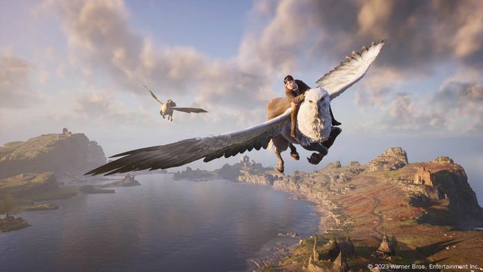 Ein Bild aus dem Spiel Hogwarts Legacy zeigt zwei Figuren, die auf Kreaturen zwischen Vogel und Pferd über eine felsige Uferlandschaft fliegen