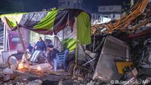 People take rest next to bonfire in the rubble in Hatay, after a 7.8-magnitude earthquake struck the country's southeast on February 6, 2023. - A major 7.8-magnitude earthquake struck Turkey and Syria, killing more than 3,000 people and flattening thousands of buildings as rescuers dug with bare hands for survivors. (Photo by BULENT KILIC / AFP)