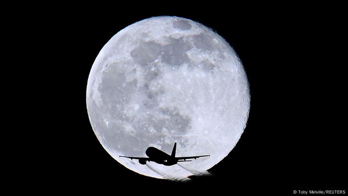 La silueta de un avión impresa sobre una enorme luna llena. 