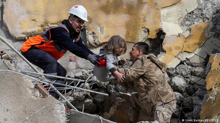 Rescatistas ayudando a una menor a salir de los escombros de un edificio. 