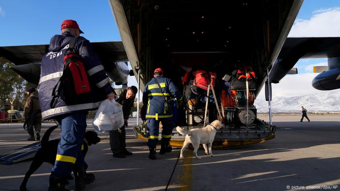 Griechische Feuerwehrleute mit Hunden besteigen ein Militärflugzeug