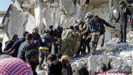 Rescuers carry a victim on the rubble as the search for survivors continues in the aftermath of an earthquake, in rebel-held town of Jandaris, Syria