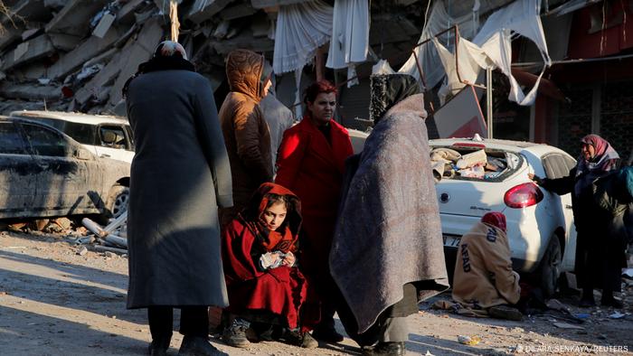 Ein Mädchen und mehrere Frauen vor zerstörten Häusern im türkischen Kahramanmaras