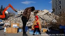 A person interacts with a child who was seated amid crates of water in the aftermath of a deadly earthquake in Kahramanmaras, Turkey, February 8, 2023. REUTERS/Suhaib Salem