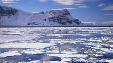 Landschaft Arktis Luftaufnahme von Küste felsig schneebedeckt eisbedeckt im Polarmeer Nordpolarmeer tiefblau unter Himmel blau teils wolkig im Vordergrund Treibeis Feld aerial view of snow-covered Ice-Covered coast of deep blue Northern Polar Sea under blue partly cloudy sky drift ice field in foreground Landschaften landscape Landscapes Meeresstraße passage passages strait Straits sounds Arctic Glaziologie glaciology geology global warming Abschmelzen Globale Erwärmung Eis Wassereis Eisblock Eisblöcke Eisbildung Eisgebilde Eislandschaft Eismeer Eisscholle Eisschollen Bildung Eisschmelze ice bergs ice ice floe ice floes ice formations ice and water ice in sea ice in water North Kent Island Jones Sound Hell's Gate Territorium Nunavut region Nordkanada Kanada Nordamerika Northern Canada North America