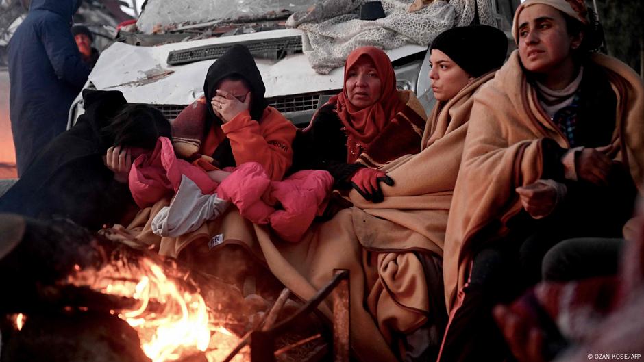 土耳其人們坐在倒塌建築物廢墟中的篝火旁