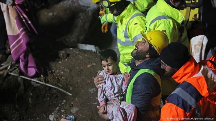 Equipos de rescate actuando. En el centro de la imagen, un rescatista con un infante en brazos.