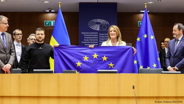 Personas en un Parlamento. Un hombre y una mujer sostienen una bandera de la UE.