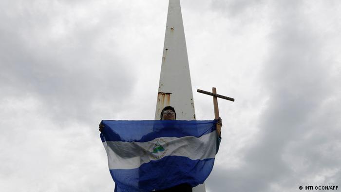 Foto simbólica de una persona que sostiene una bandera de Nicaragua y una cruz en una imagen de archivo.
