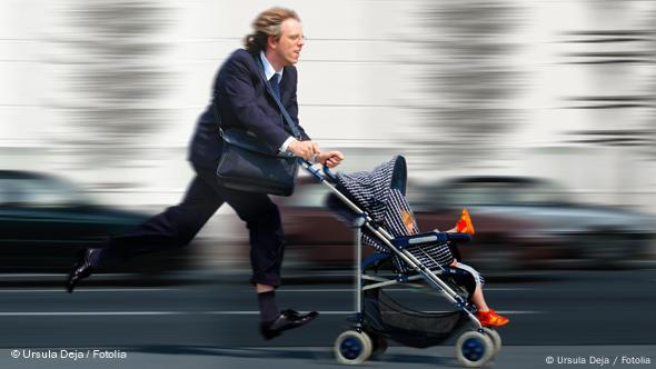 Foto de archivo de un hombre con traje que corre empujando un coche infantil.