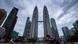 Die Petronas Twin Towers in Kuala Lumpur, im Vordergrund Autos und ein Fahrradfahrer, der einen Maske trägt. Die Petronas Twin Towers in Kuala Lumpur, im Vordergrund Autos und ein Fahrradfahrer, der einen Maske trägt.