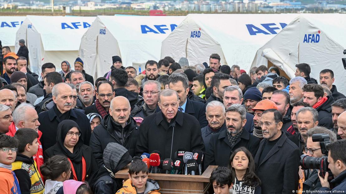 Presidente turco, Recep Tayyip Erdogan fala à imprensa cerdado por populares em frente a barracas de desabrigados pelo terremoto