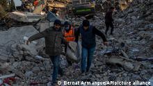 Men carry the body of an earthquake victim in Antakya, southeastern Turkey, on Saturday, February 11, 2023. (AP Photo/Bernat Armangue)