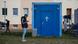 refugee checks his mobile phone standing nex to the entrance to a temporary prayer room