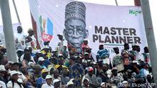 upporters sit beside a banner of presidential candidate of All Progressives Congress (APC) Bola Tinubu during the party campaign rally at Teslim Balogun Stadium in Lagos, on November 26, 2022. 