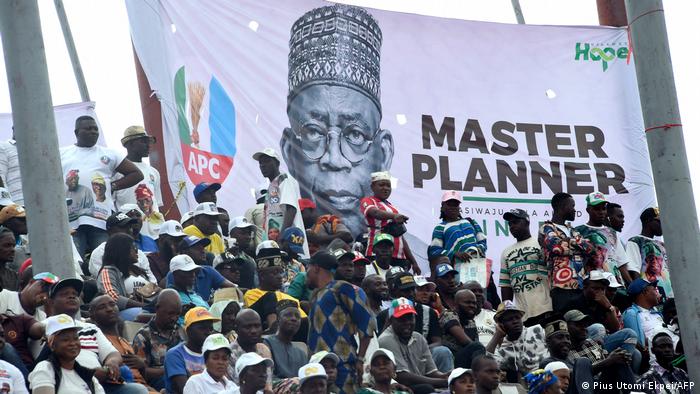 Nigeria: Anhänger des Präsidentschaftskandidaten Bola Tinubu sitzen vor einem Plakat, das ihn als Master Planner bezeichnet, November 2022 (Foto: Pius Utomi Ekpei/AFP)