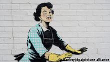Dieses undatierte Handout-Foto zeigt eines der neuen Werke von Banksy, das eine Hausfrau aus den 1950er Jahren zu zeigen scheint, die eine klassische blaue Schürze und gelbe Abwaschhandschuhe trägt, mit einem geschwollenen Auge und einem fehlenden Zahn, die ihren männlichen Partner in eine Gefriertruhe zu schubsen scheint. (zu dpa «Banksy mit Graffiti gegen häusliche Gewalt zum Valentinstag») +++ dpa-Bildfunk +++