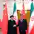 Händedruck zwischen Irans Präsident Ebrahim Raisi und seinem chinesischen Amtskollegen Xi Jinping mit Flaggen beider Länder