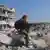 رجل يقف على أنقاض بيوت دمرها الزلزال في بلدة جنديرس شمال غرب سوريا