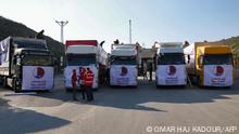 13/02/2023 Men stand next to trucks, part of a convoy carrying aid provided by Qatar, in the aftermath of an earthquake, at Syria's Bab al-Hawa border crossing with Turkey in the rebel-held northwestern province of Idlib, on February 13, 2023. (Photo by OMAR HAJ KADOUR / AFP)