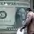 A man in Cairo walks past a foreign exchange office with a huge dollar note poster
