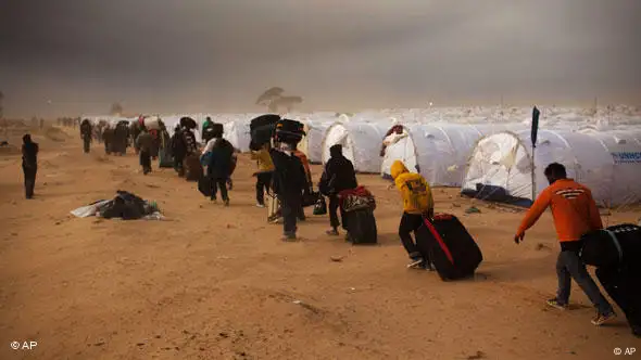 Eine Reihe von Männern trifft aus Libyen trifft in einem Flüchtlingscamp in Ras Ajdir, nahe der tunesisch-libyischen Grenze, ein (Foto: AP)