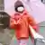 A girl covered in face mask and rain coat carrying umbrella