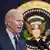 US President Joe Biden stands in front of a picture of the seal of the president of the United States
