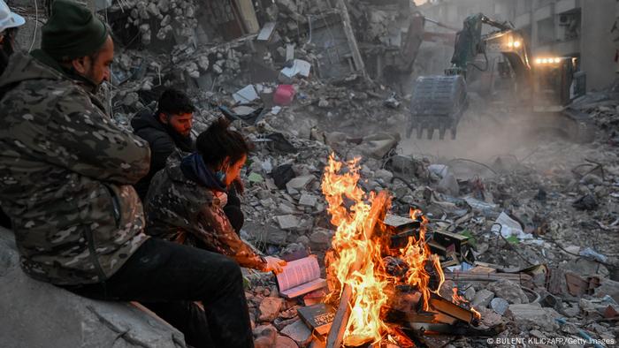 Sobrevivientes queman libros en una fogata, para calentarse, en Hatay.