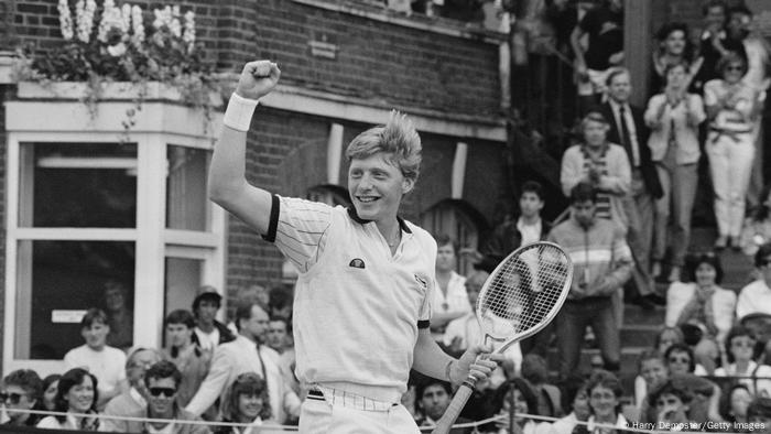 Boris Becker reckt eine Faust in die Luft und hält einen Tennisschläger in die Luft.