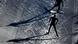 Two biathletes compete, long shadows behind them Two biathletes compete, long shadows behind them