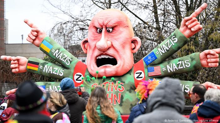El jefe del Grupo Wagner en Ucrania, Yevgueni Prigozhin, con múltiples brazos que señalan hacia Ucrania, Alemania, Estados Unidos, y la OTAN denunciando que allí hay nazis.