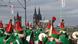Eine Truppe verkleideter Personen schreitet beim Rosenmontagsumzug in Köln über eine Brücke. Im Hintergrund sieht man den Kölner Dom. Eine Truppe verkleideter Personen schreitet beim Rosenmontagsumzug in Köln über eine Brücke. Im Hintergrund sieht man den Kölner Dom.