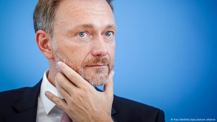 Portraitaufnahme von Bundesfinanzminister Christian Lindner. Er blickt ernst und hat Daumen und Zeigefinger der linken Hand an sein Kinn gelegt. 