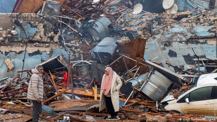 Un hombre y una mujer observan las ruinas de un edificio colapsado por el terremoto en Turquía.