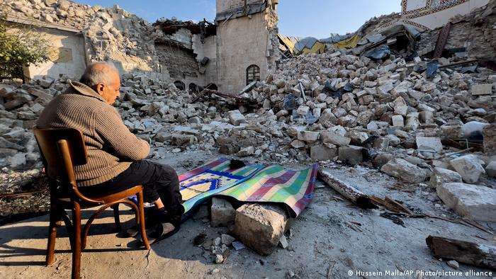 Ein Mann sitzt und betet vor den Ruinen einer Moschee in der Stadt Hatay