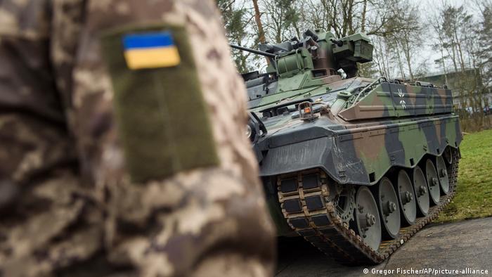 Un soldado ucraniano de pie frente a un vehículo de infantería Marder.