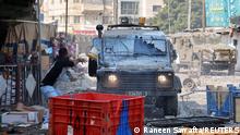 A Palestinian hurls a paint bucket at an Israeli military vehicle during a raid in Nablus in the Israeli-occupied West bank, February 22, 2023. REUTERS/Raneen Sawafta