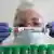 In einem Labor hält eine Person ein Reagenzglas mit der englischen Aufschrift für Vogelgrippe zwischen den Händen 