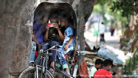 Children play games on smartphones as they sit in a Rickshaw in Dhaka, Bangladesh