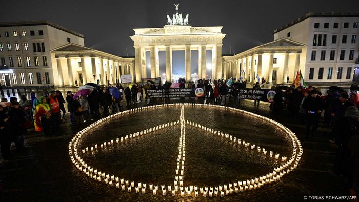 Protesta contra un año de guerra en Ucrania, en Berlín, en la Puerta de Brandeburgo: el símbolo de la paz iluminado con velas.