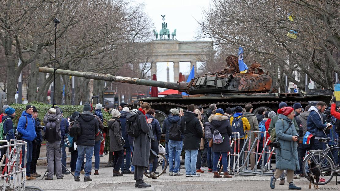 People gather around a damaged Russian tank on show near the site of Russia's embassy in Berlin. February 24, 2023. 