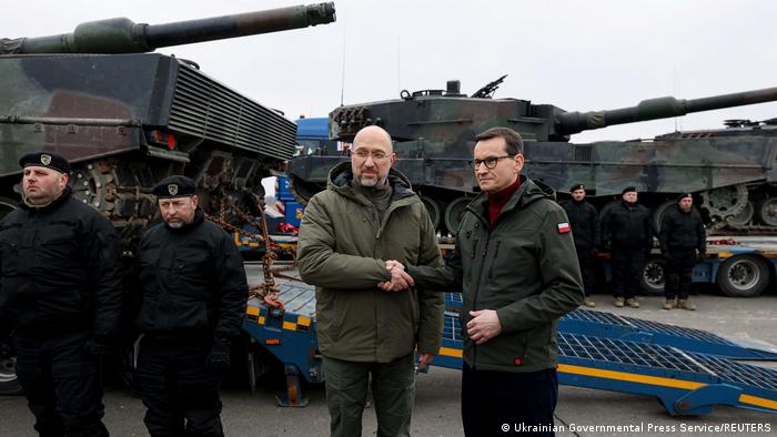 Polens Regierungschef Mateusz Morawiecki und der ukrainische Ministerpräsident Denis Schmyhal schütteln sich vor Panzern die Hände 