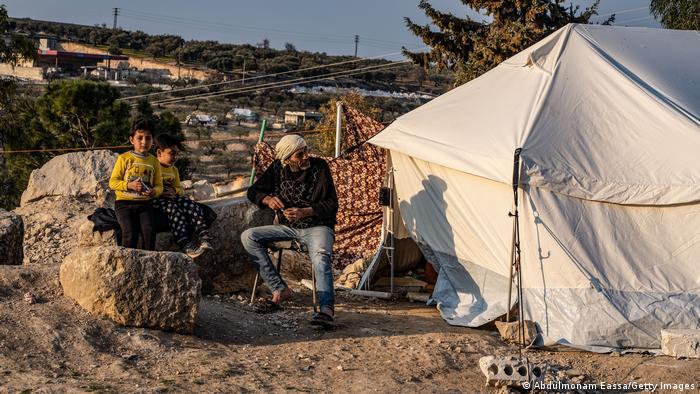 Ein Mann und zwei Jungen sitzen vor einem weißen Zelt, in Idlib im Nordwesten von Syrien