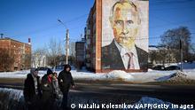 Pedestrians walk past a mural of Russian President Vladimir Putin on a residential building in the town of Kashira, south of Moscow, on February 23, 2023. (Photo by Natalia KOLESNIKOVA / AFP) (Photo by NATALIA KOLESNIKOVA/AFP via Getty Images)