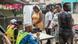 Pessoas em pequena fila para votar em local a céu aberto Pessoas em pequena fila para votar em local a céu aberto