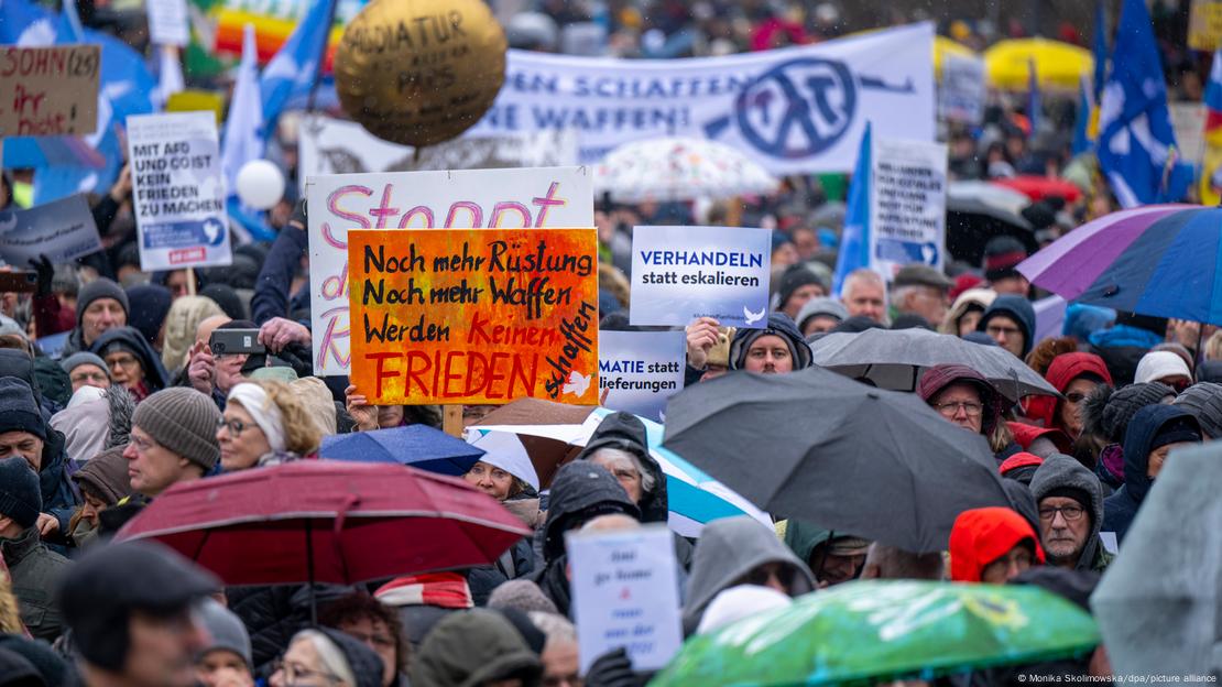 Demonstrators at a rally calling for talks between Russia and Ukraine in Berlin in large crowd, holding banners. February 26, 2023. 