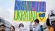 Demonstranten halten ein Schild "Stand with Ukraine" hoch Demonstranten halten ein Schild "Stand with Ukraine" hoch