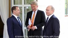 Russian President Vladimir Putin (R), the presidential spokesman Dmitry Peskov (C) and Prime Minister Dmitry Medvedev (L) speak before their meeting with German Chancellor in Sochi on May 18, 2018. (Photo by Mikhail KLIMENTYEV / SPUTNIK / AFP) (Photo by MIKHAIL KLIMENTYEV/SPUTNIK/AFP via Getty Images)